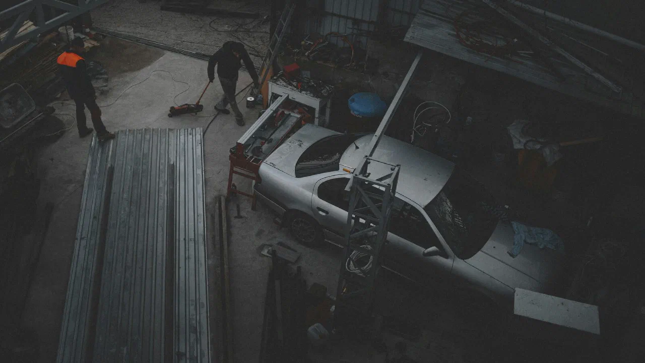 Two people working on a car raised in a repair shop